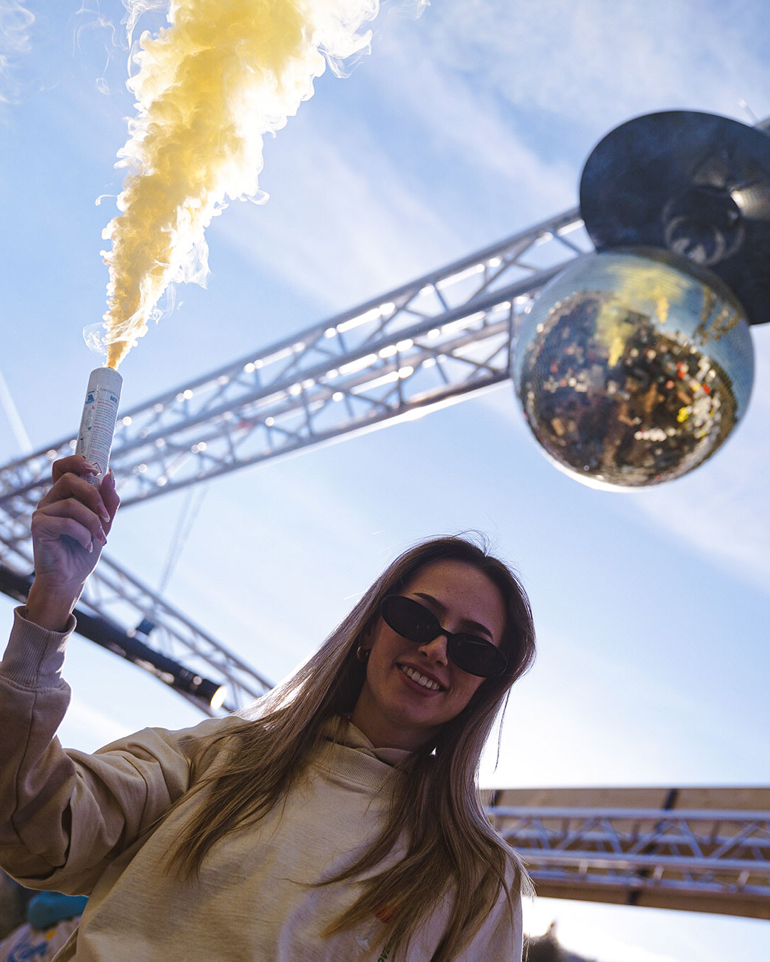Ragazza che tiene in aria un bengala e dietro di lei una palla da discoteca - Alpres Ristorante Après Ski