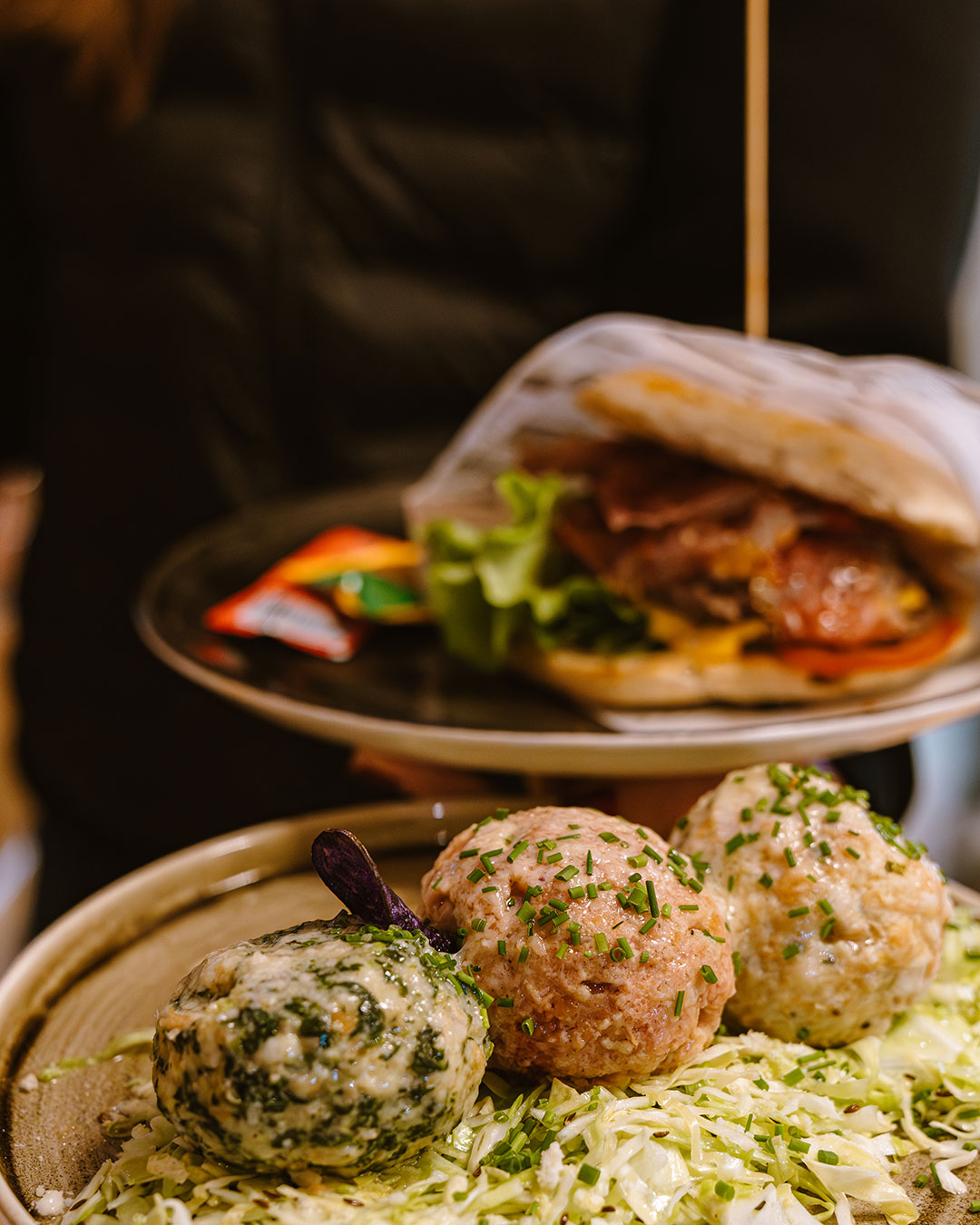 Knödeltris mit Krautsalat und dahinter ein Burger - Alpres Restaurant Après Ski