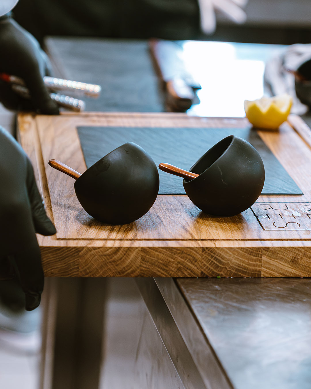 Zwei schwarze Schälchen auf einer Holzplatte - Alpres Restaurant Après Ski