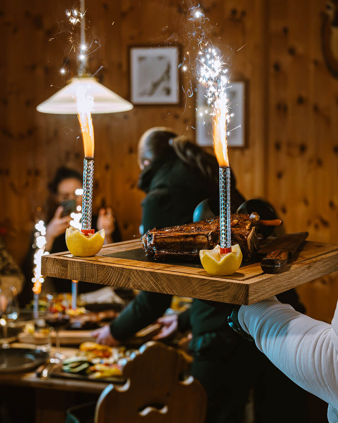 Steak auf einem Brett mit zwei Zitronen und Wunderkerzen - Alpres Restaurant Après Ski