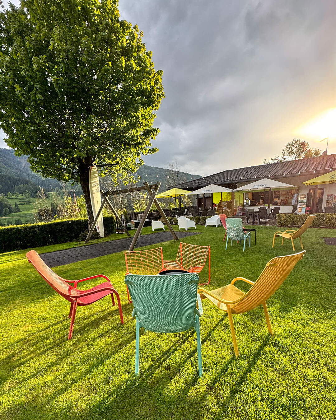Der Garten mit Schaukel und Blick auf die Terrasse im Freibad in Welsberg - Alpres Restaurant Après Ski